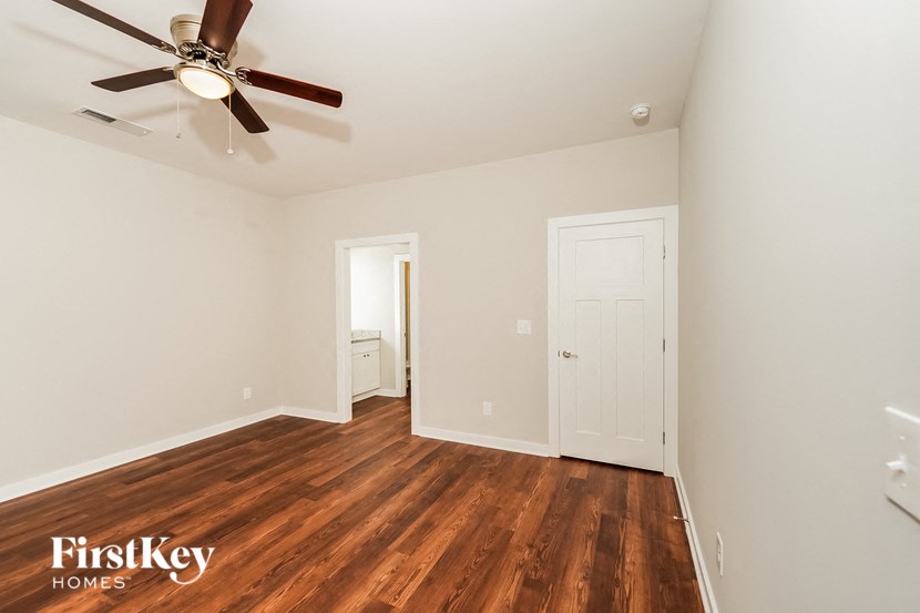 a bedroom with a ceiling fan and wood flooring