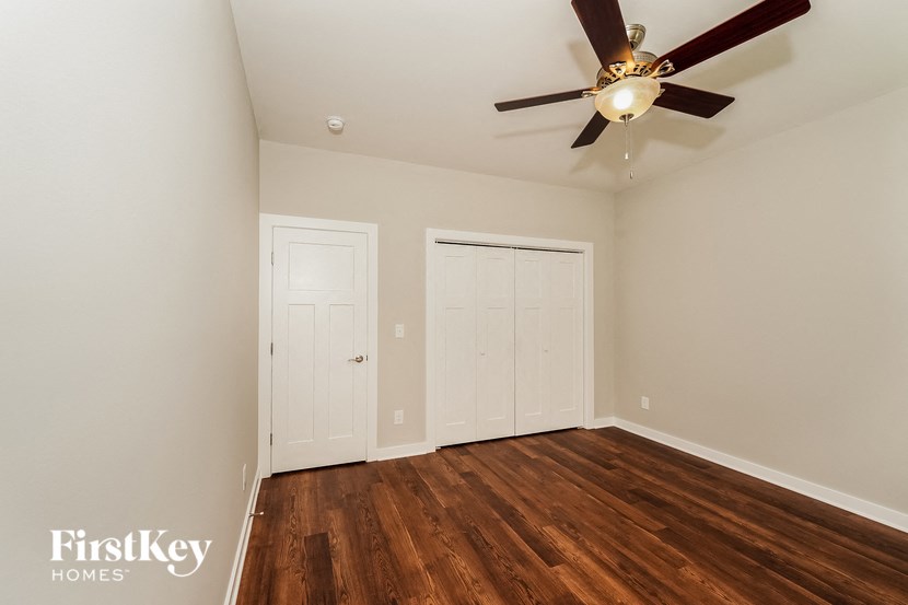 a bedroom with wood flooring and a ceiling fan