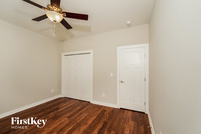a bedroom with wood flooring and a ceiling fan
