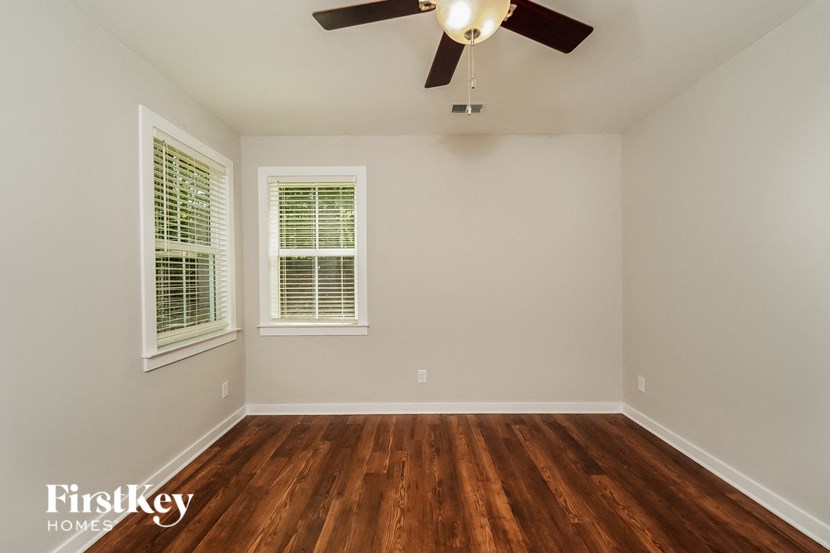 an empty room with a ceiling fan and wood floors