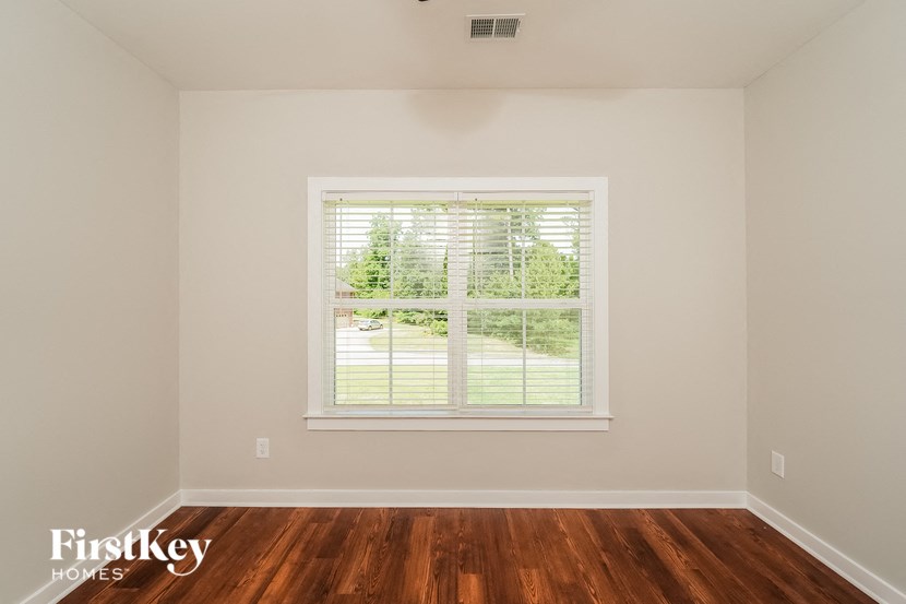 a bedroom with a window and wood floors