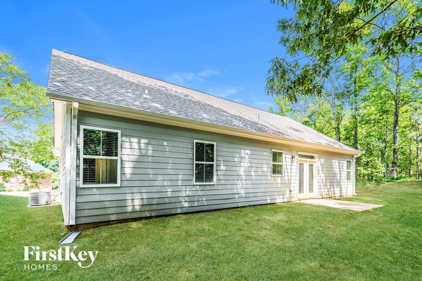 a small white house with a grass yard and trees