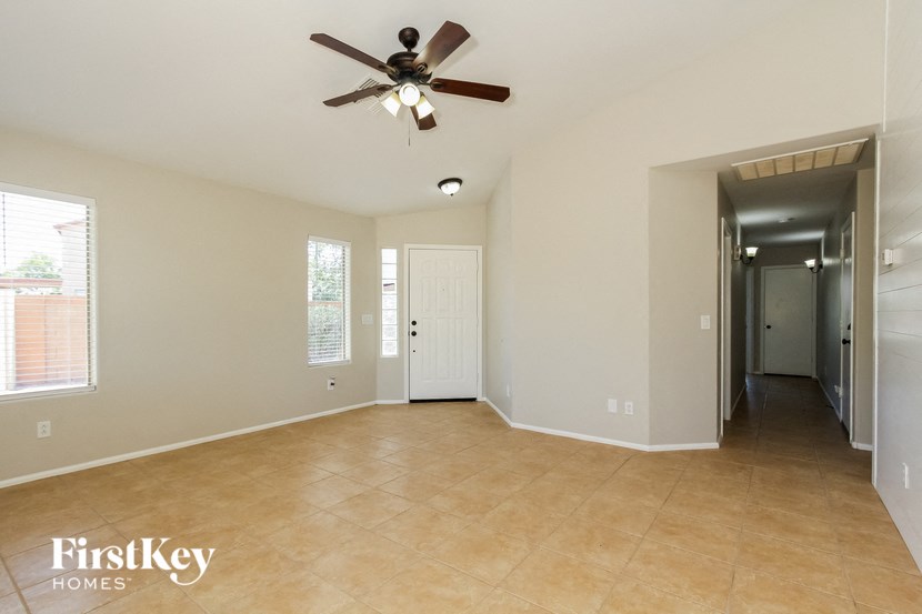 an empty living room with a ceiling fan and a hallway
