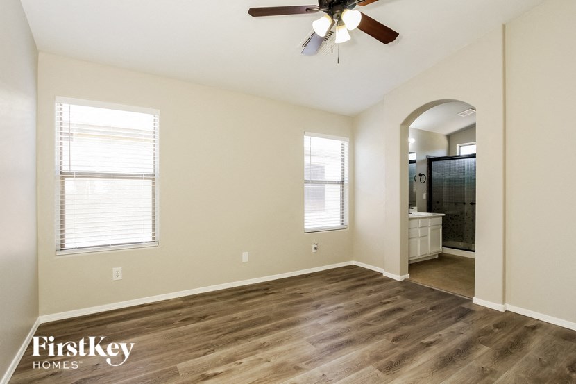 the spacious living room with hardwood flooring and a ceiling fan