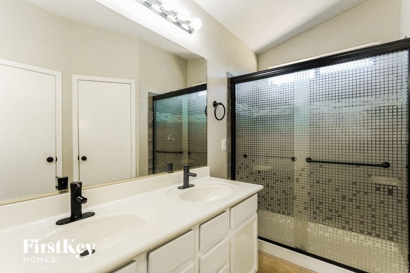 a bathroom with a sink and a shower and a mirror