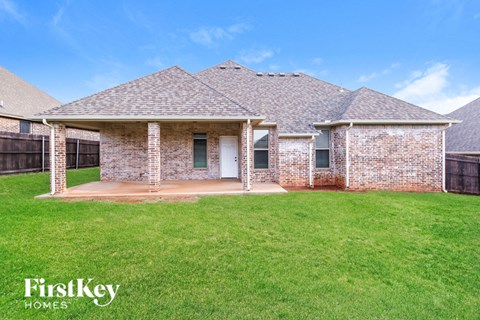 front view of a brick house with a yard and grass