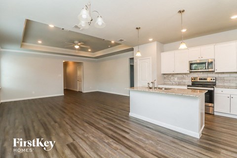 an open kitchen and living room with white cabinets and a counter top