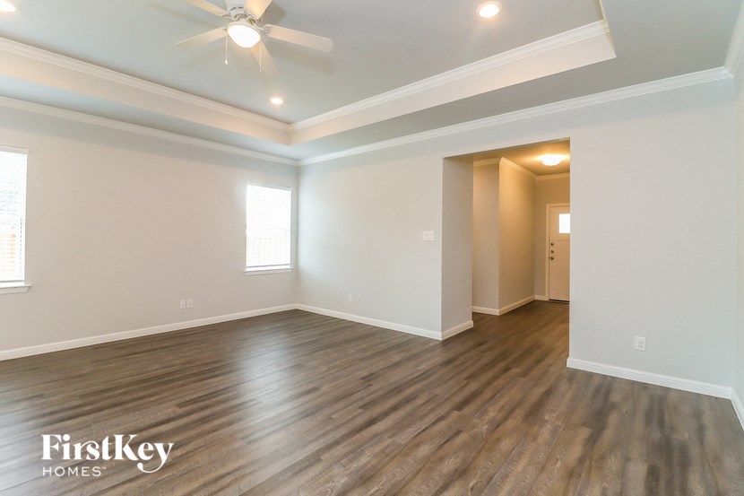 the spacious living room with hardwood flooring and a ceiling fan