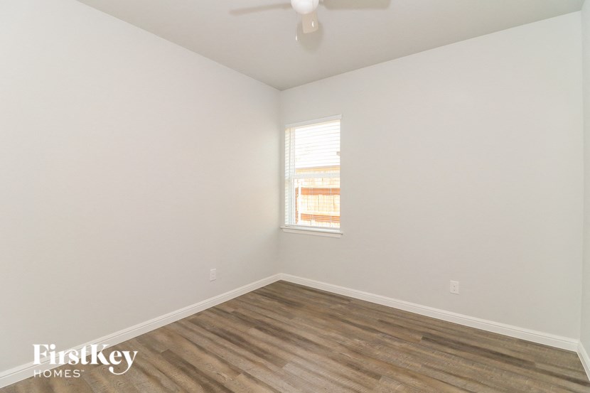 a bedroom with white walls and wood flooring and a window