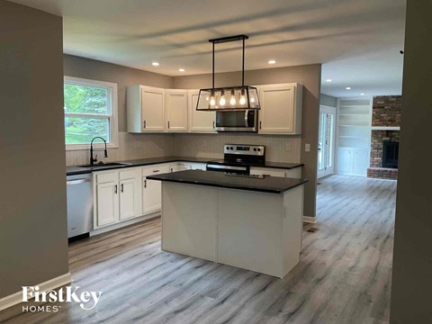 a kitchen with white cabinets and a black counter top