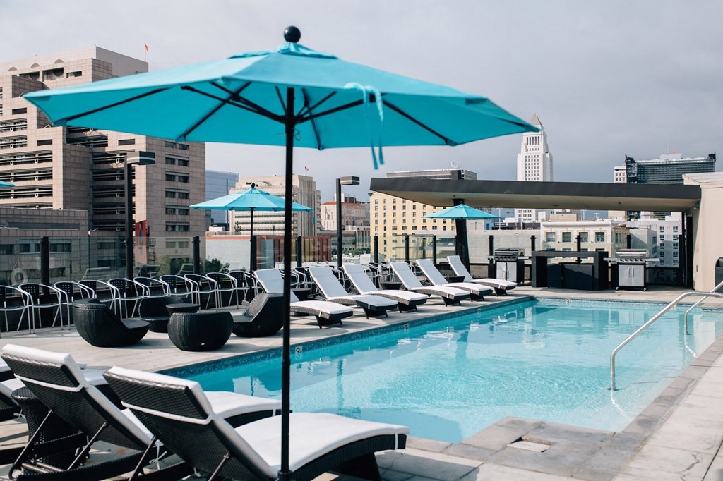a pool with chairs and umbrellas on top of a building