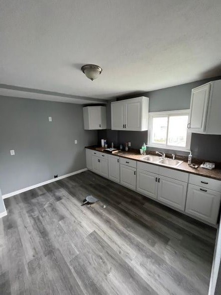 A kitchen with white cabinets and a grey floor.