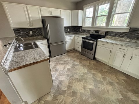 A kitchen with a granite countertop and white cabinets.
