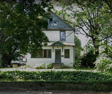 A white house with a grey roof and a green door.