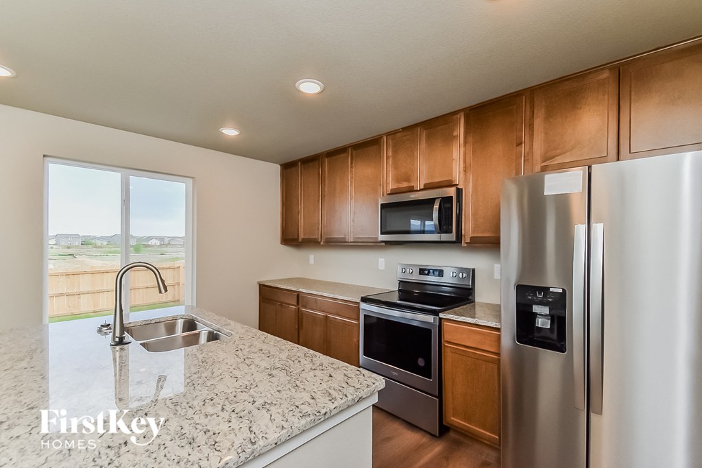 a kitchen with granite counter tops and wooden cabinets and stainless steel appliances