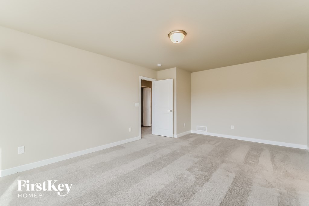 a spacious living room with carpet and a door to a hallway