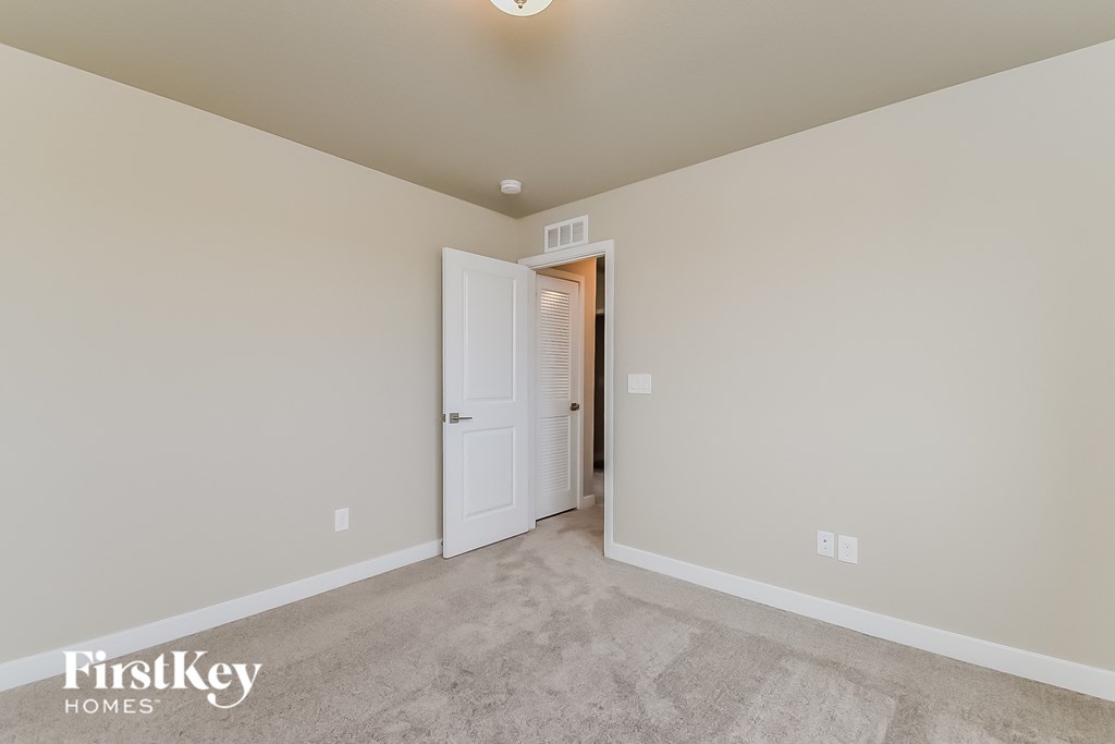 a master bedroom with a carpeted floor and a door to a closet