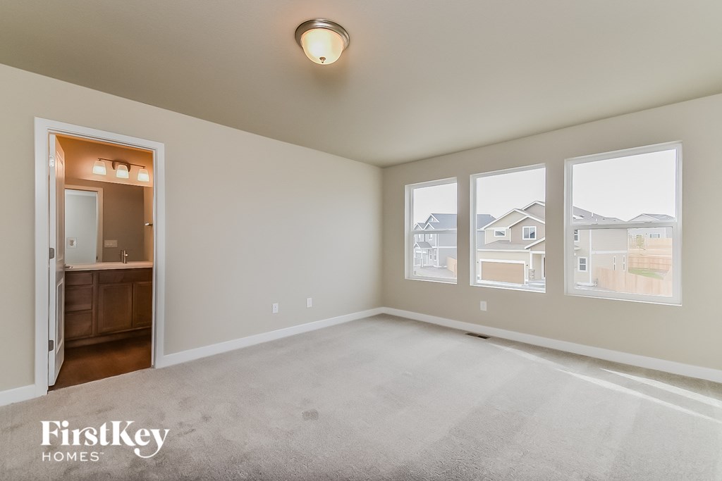an empty living room with three windows and a door to a bathroom