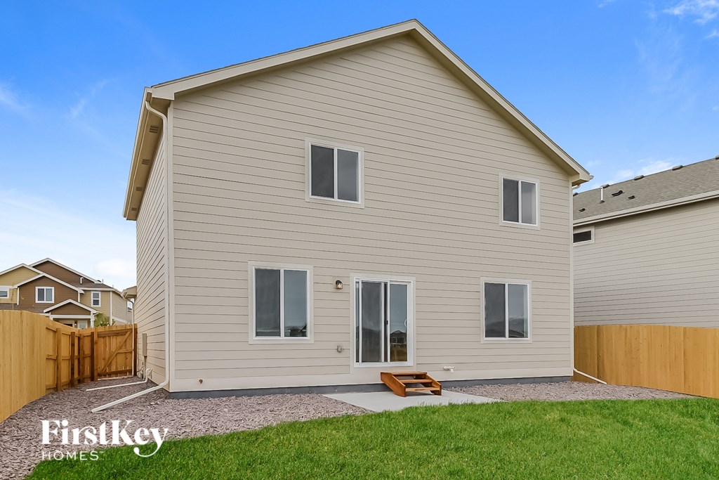 a white house with a wooden fence and a lawn