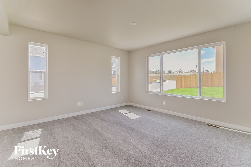 A spacious room with a view of a fence and trees through the window.