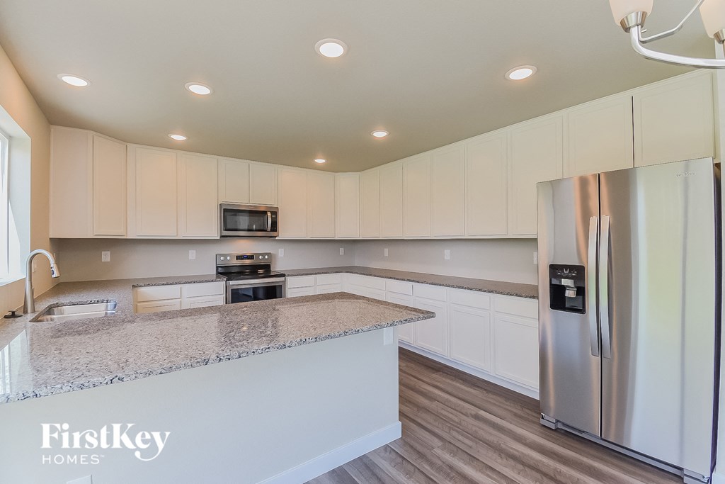 A kitchen with a granite countertop and stainless steel appliances.