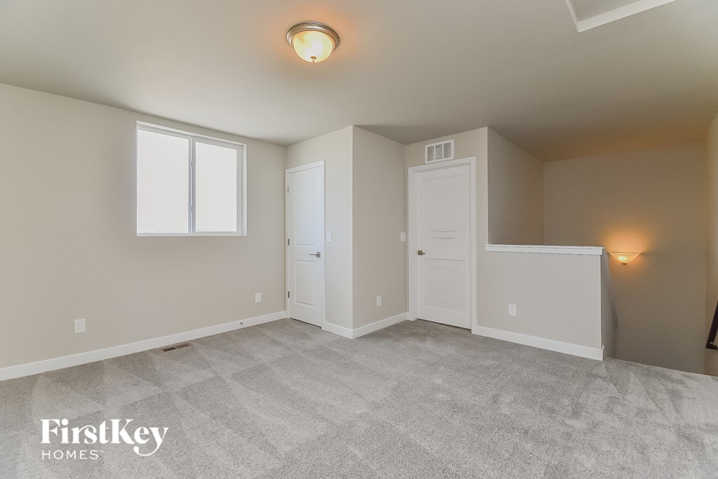 A spacious room with a carpeted floor and two doors.