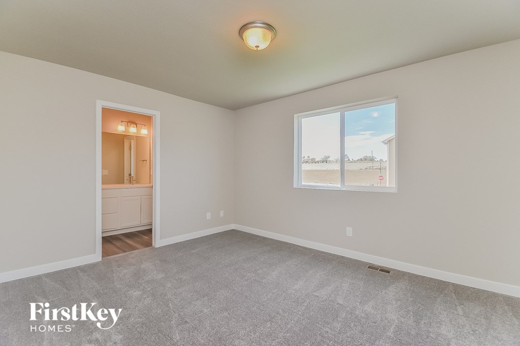 A room with a carpeted floor and a window showing a view of a parking lot.