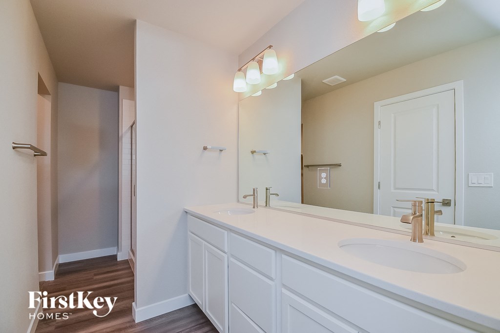 A bathroom with a sink, mirror, and a shower.