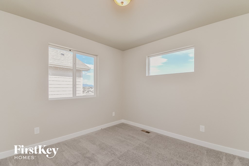 A room with a carpeted floor and two windows.