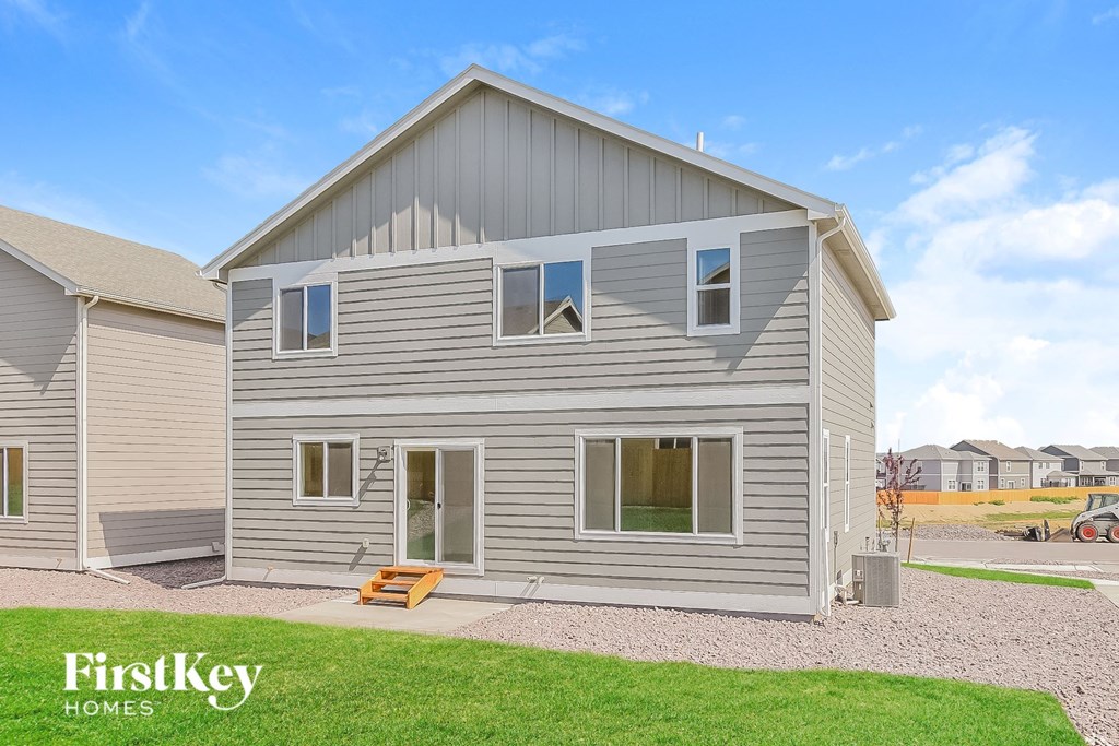 A house with a grey siding and a brown door is shown.