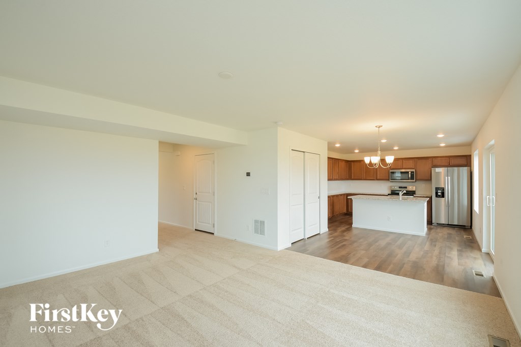 an empty living room and kitchen with white walls and wood flooring