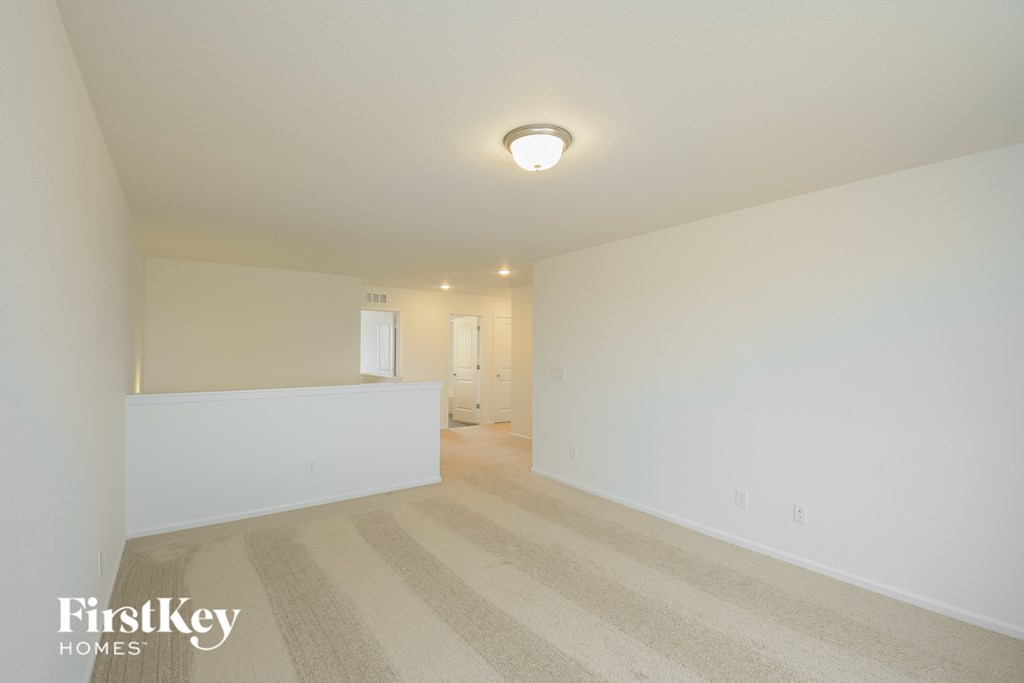 a spacious living room with carpet and white walls