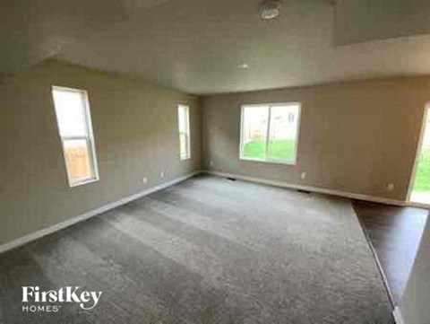 an empty living room with windows and a rug