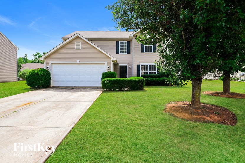 a beige house with a white garage door and a tree