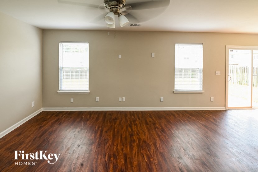 a empty living room with wood floors and a ceiling fan