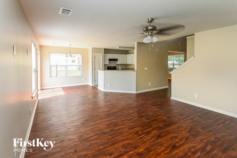 an empty living room and kitchen with wood flooring