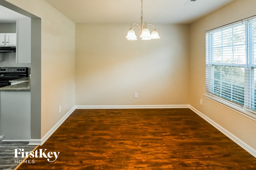 an empty dining room with wood flooring and two windows