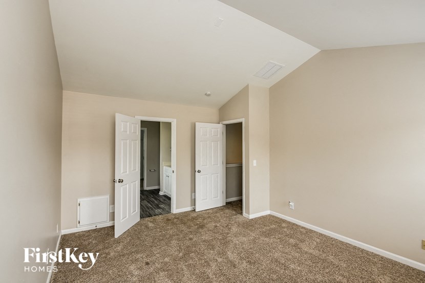a bedroom with a carpeted floor and a doorway to a closet