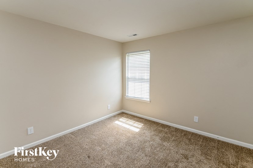 a large empty room with a window and carpet