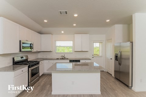 A kitchen with white cabinets and a granite countertop.