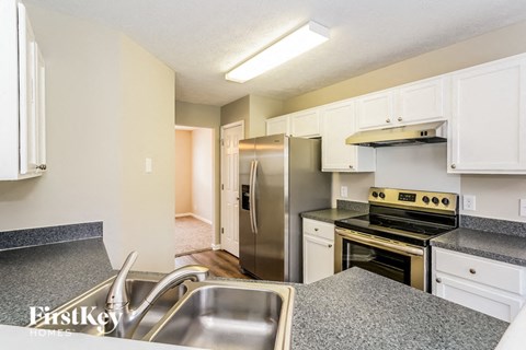 A kitchen with a stainless steel refrigerator and a stove top oven.