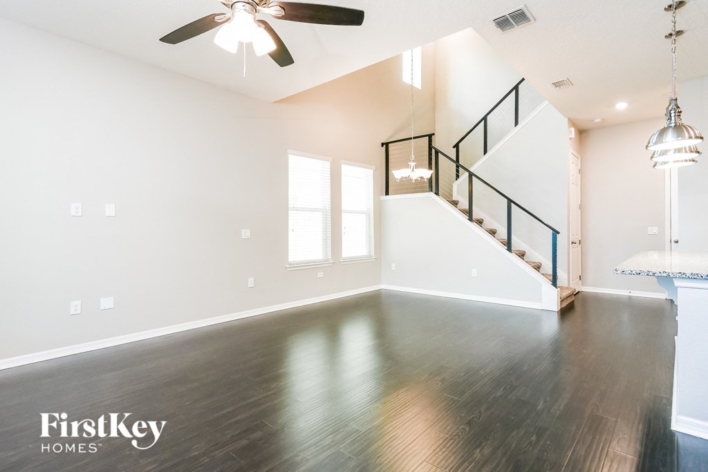 an empty living room with wood floors and a ceiling fan