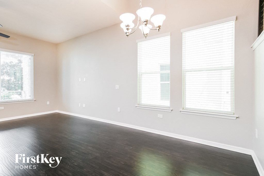 a bedroom with wood floors and three windows