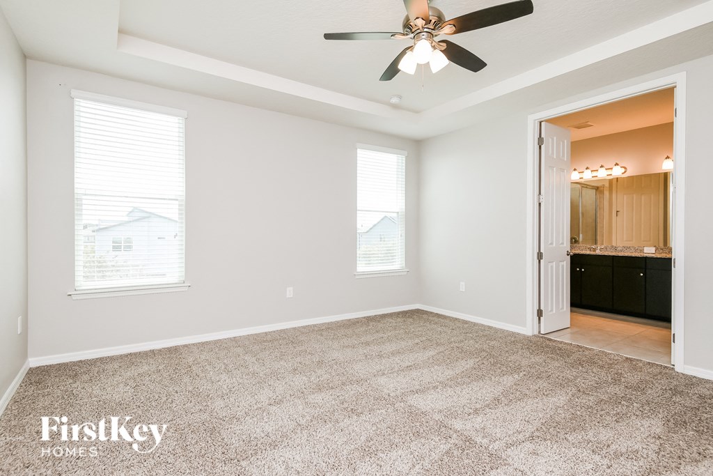 an empty living room with a ceiling fan and a kitchen
