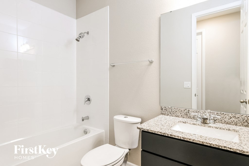 a bathroom with a toilet sink and tub and a mirror