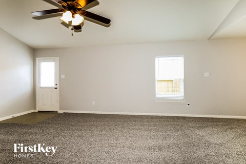 the living room of a home with a ceiling fan and carpet
