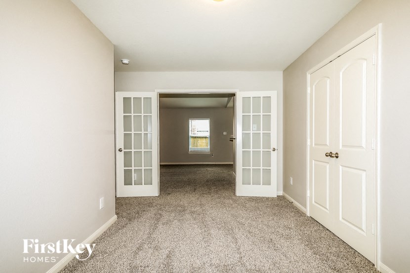 a empty living room with white doors and carpeting