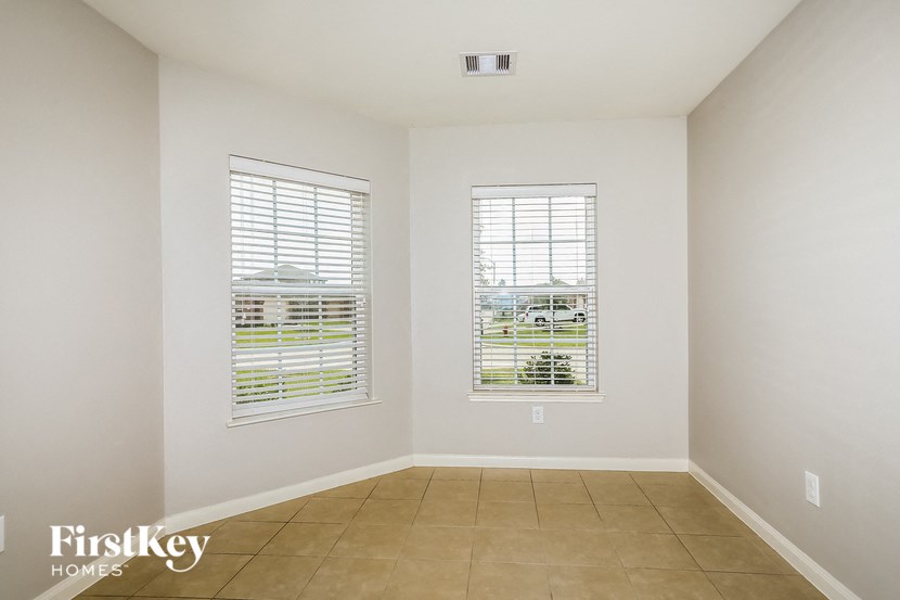 an empty room with two windows and a tiled floor