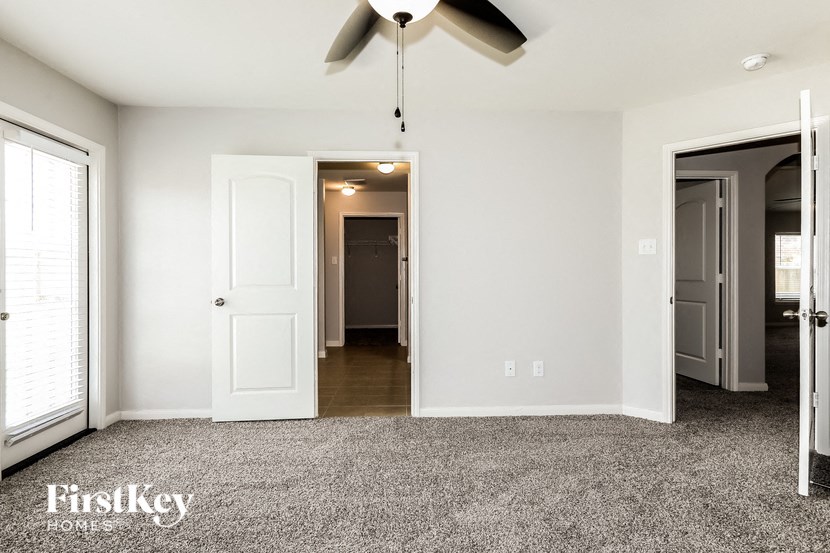 a bedroom with a ceiling fan and a door to a hallway