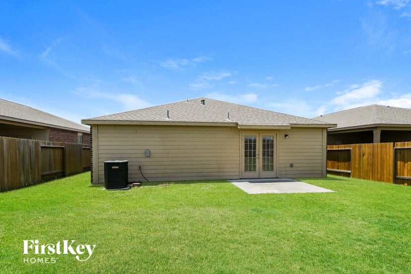 a tan house with a yard and a wooden fence
